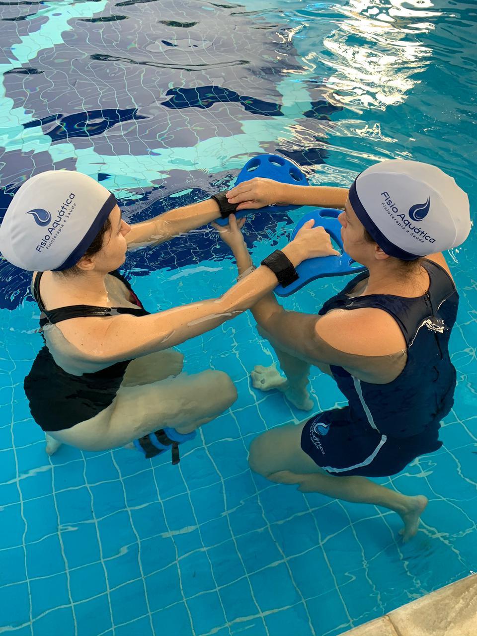 Fisioterapeuta conduzindo exercício de fisioterapia aquática na piscina aquecida da Fisio Aquática